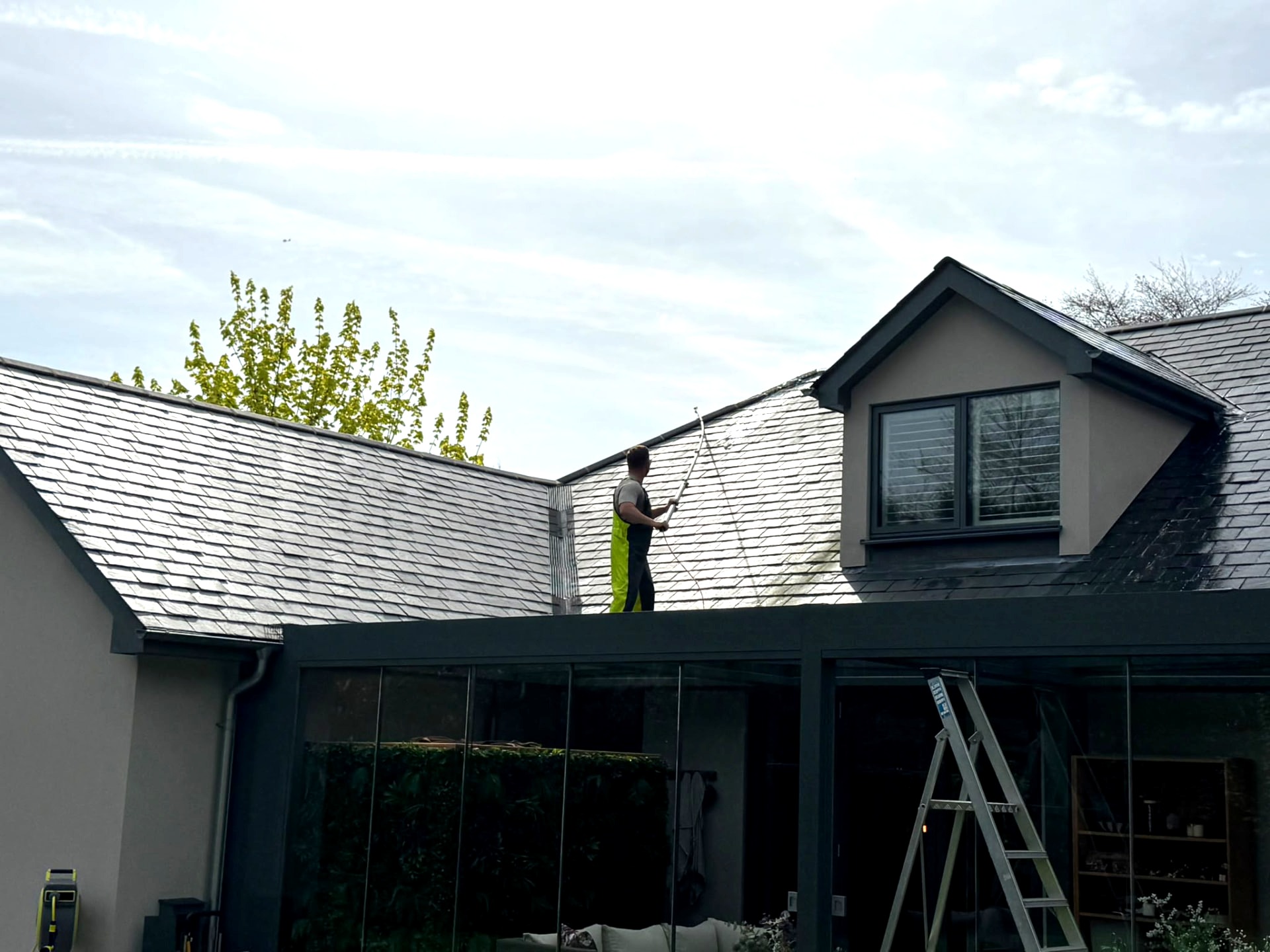 Slate roof being washed with a water-fed pole on a modern home near Lymington